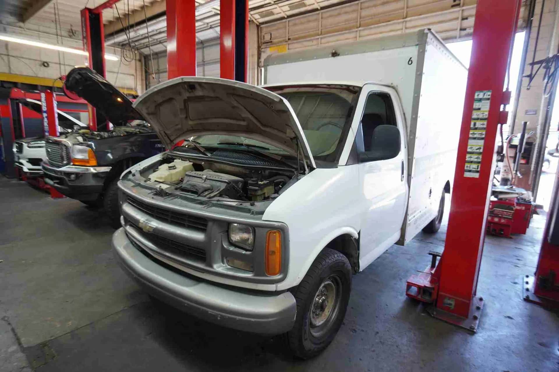 White work van on a lift inside the shop for service