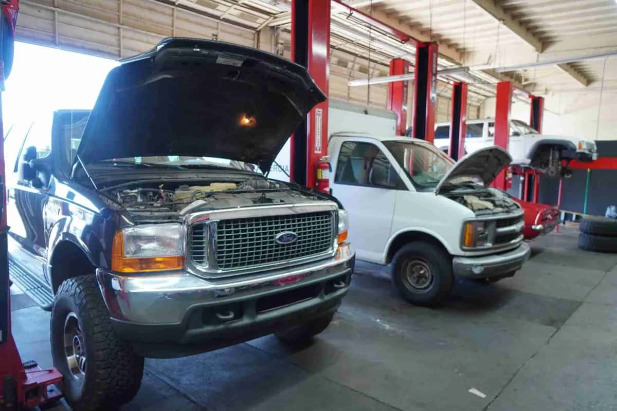 Pickup truck and van with hoods open in the service bays