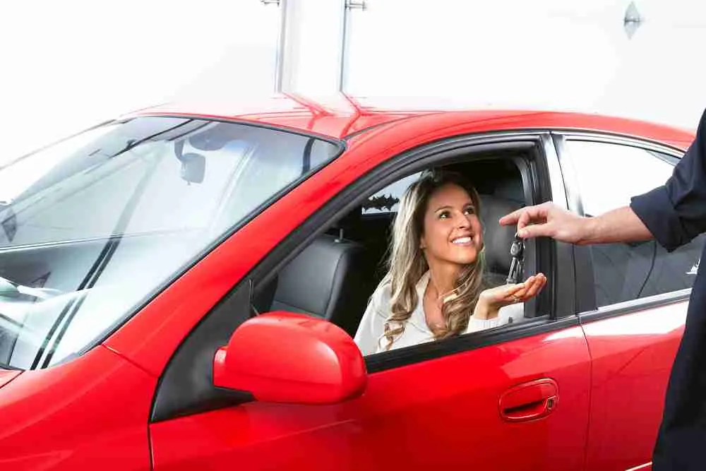 Customer in a red car handing over keys at drop-off