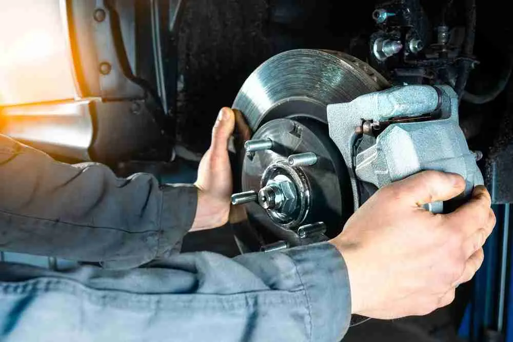 Technician holding a brake caliper over a rotor