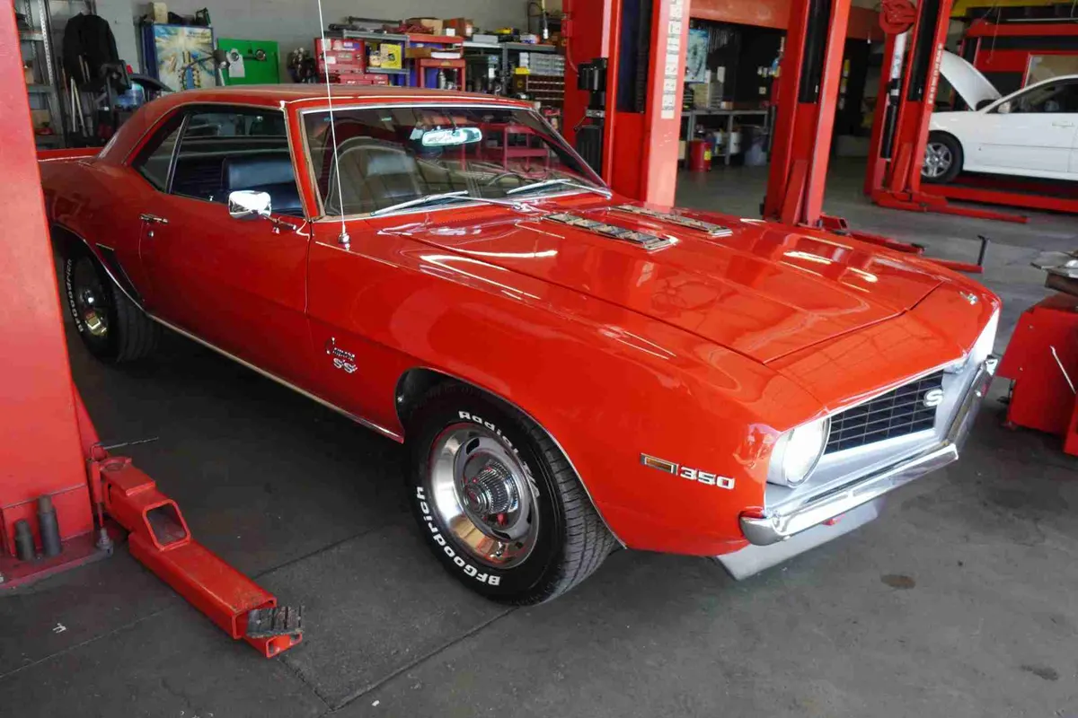 Orange classic Camaro parked in the shop