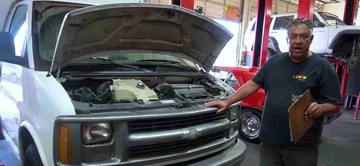 Shop team member with a clipboard beside a white work van with the hood open