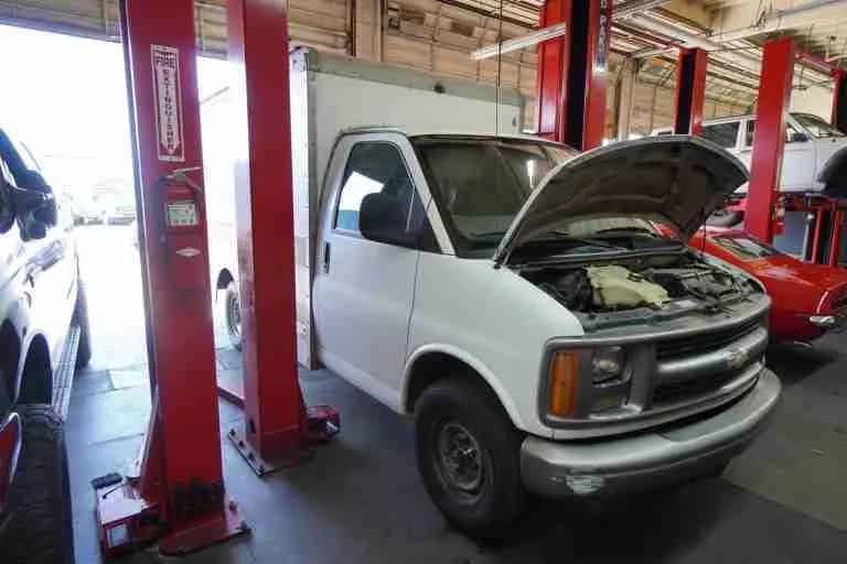 White work van with the hood open in the service bay