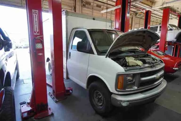 White work van with the hood open in the service bay