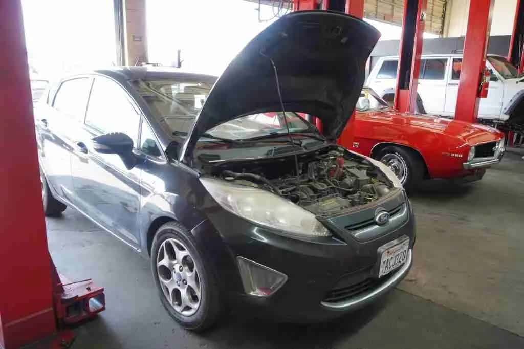Compact car with the hood open in the service bay