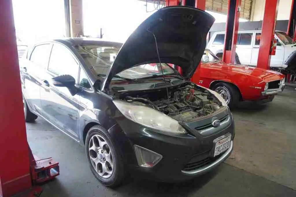 Compact car with the hood open in the service bay