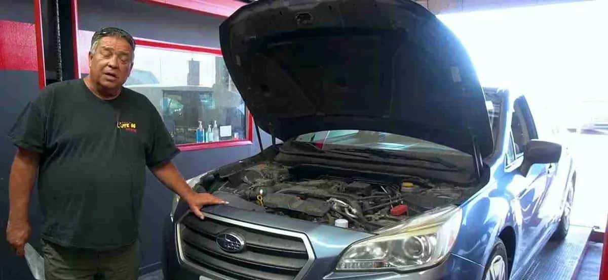 Shop team member beside a car with the hood open during an overheating diagnosis