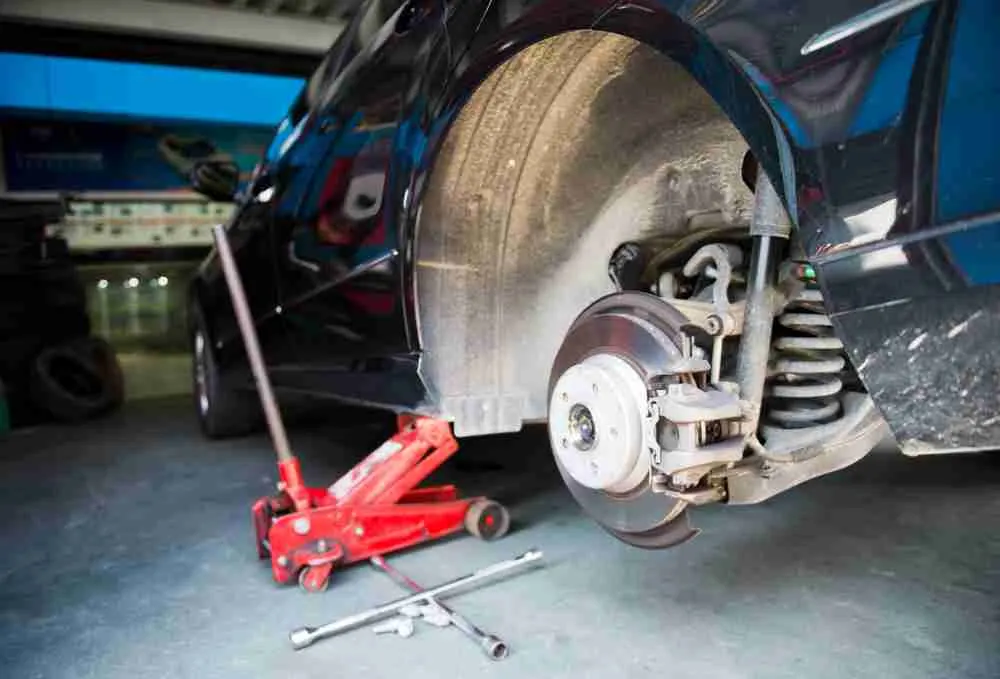 Front suspension and brake assembly on a car raised with a floor jack