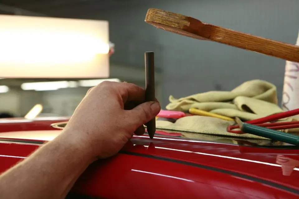 Hand working on the red paint of a car panel