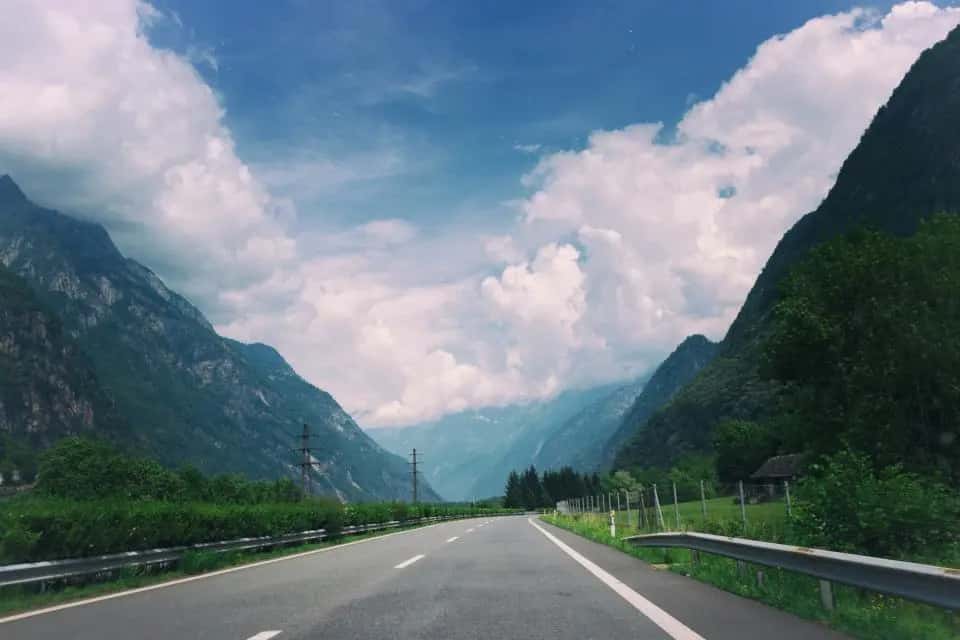 Highway leading toward mountains under a cloudy sky