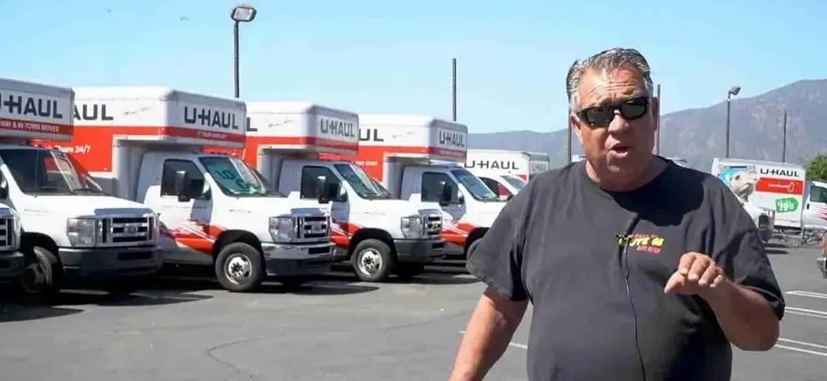 Shop team member standing in front of a row of U-Haul trucks